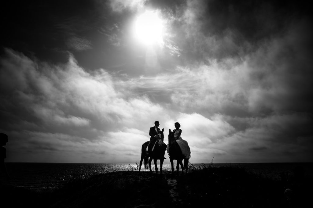 grayscale photography of couple riding on horse with body of