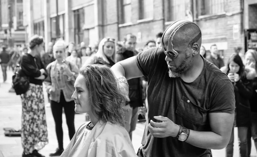 grayscale photography of man cutting hair of woman