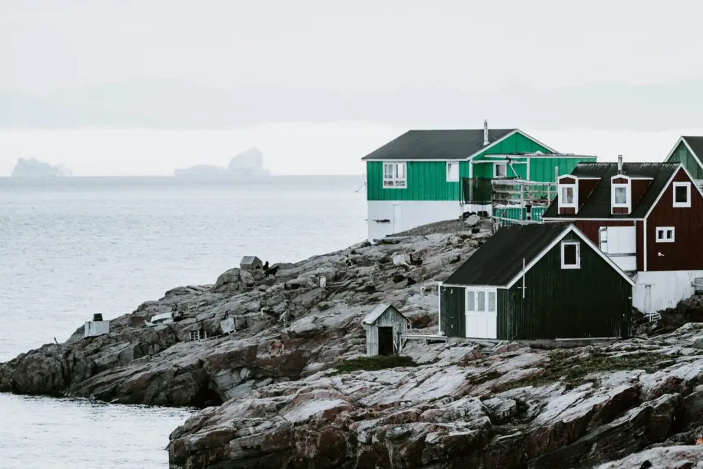 green and black house near body of water under white sky