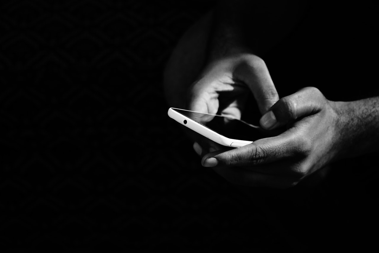 grey scale photo of person holding smartphone