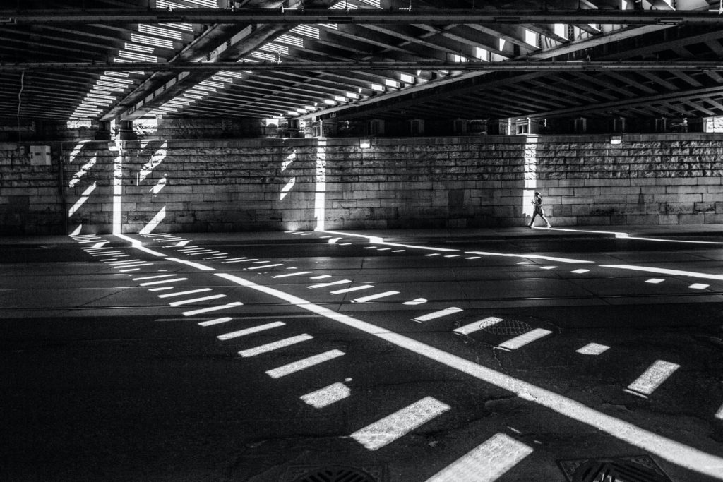 grayscale photography of man walking on road 