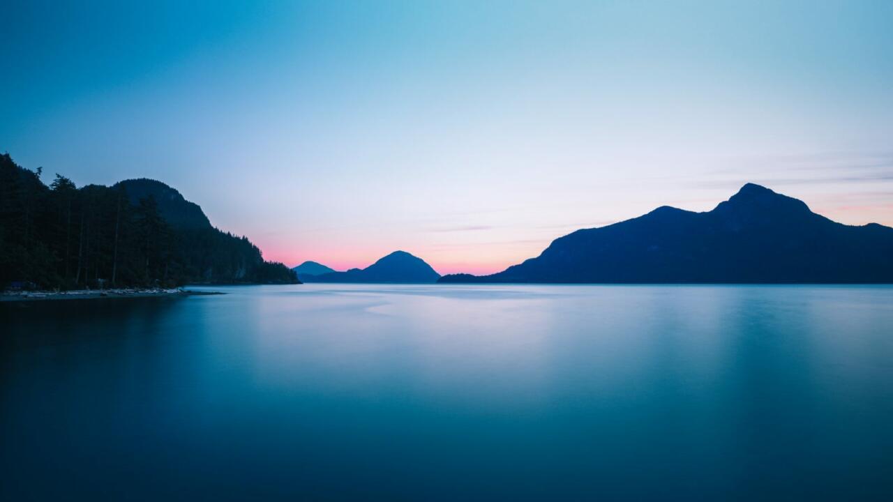 silhouette photo of mountain range near body of water