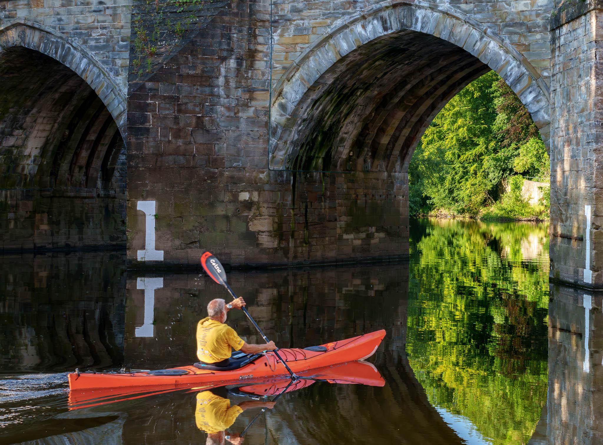 Kayaker paddles under Framwellgate Bridge in Durham UK