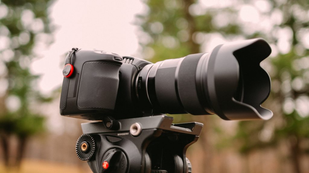 Camera with telephoto lens and lens hood on tripod. 