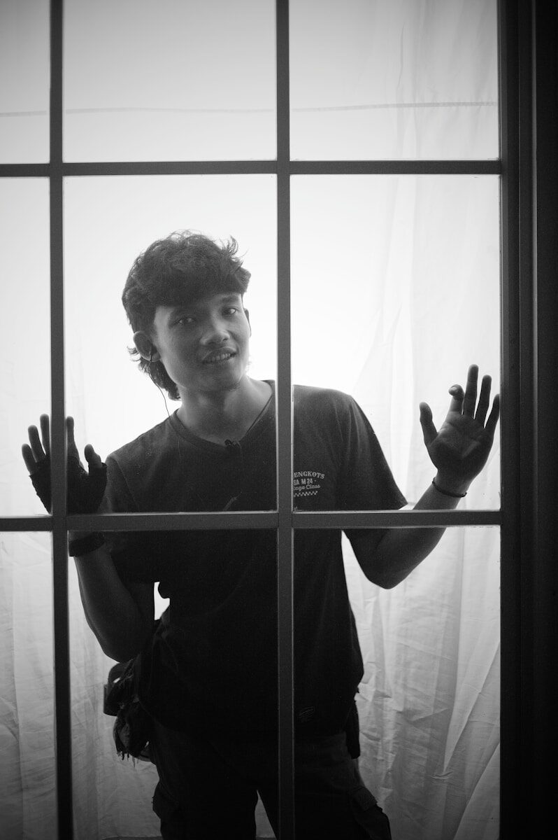 a young man standing in front of a window