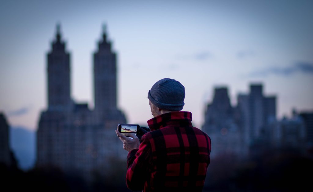Man taking camera phone photograph of skyline