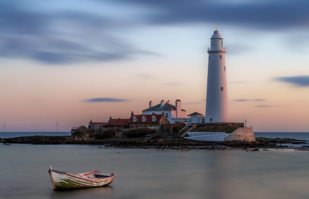 Long exposure image of St Mary's Lighthouse at dawn in NE England with AI boat added to foreground