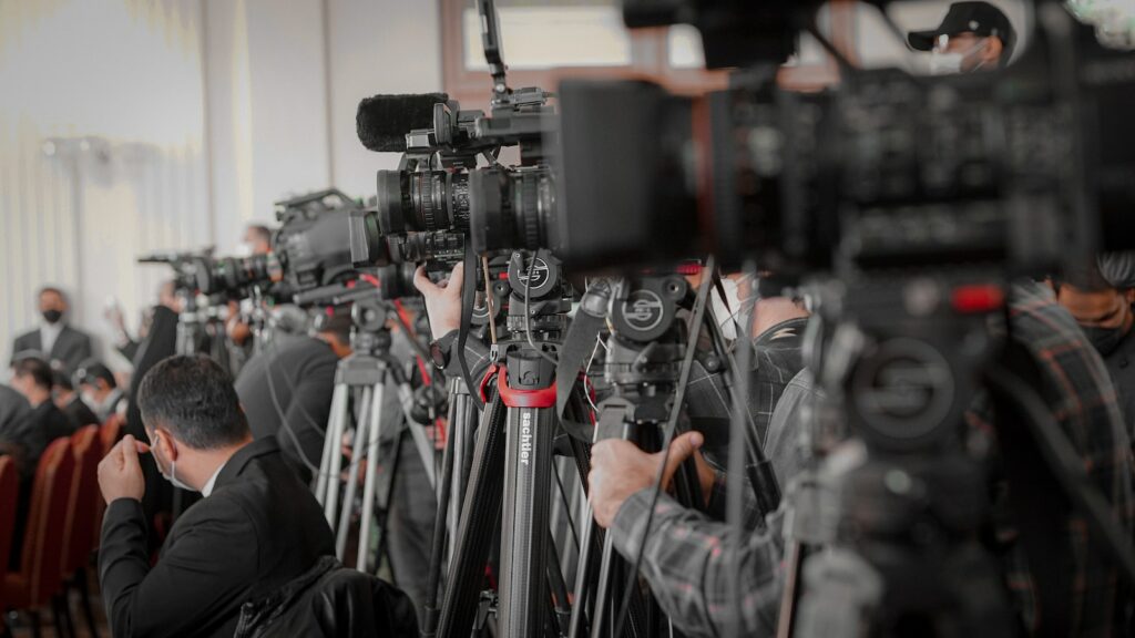 a large group of people in a room with cameras