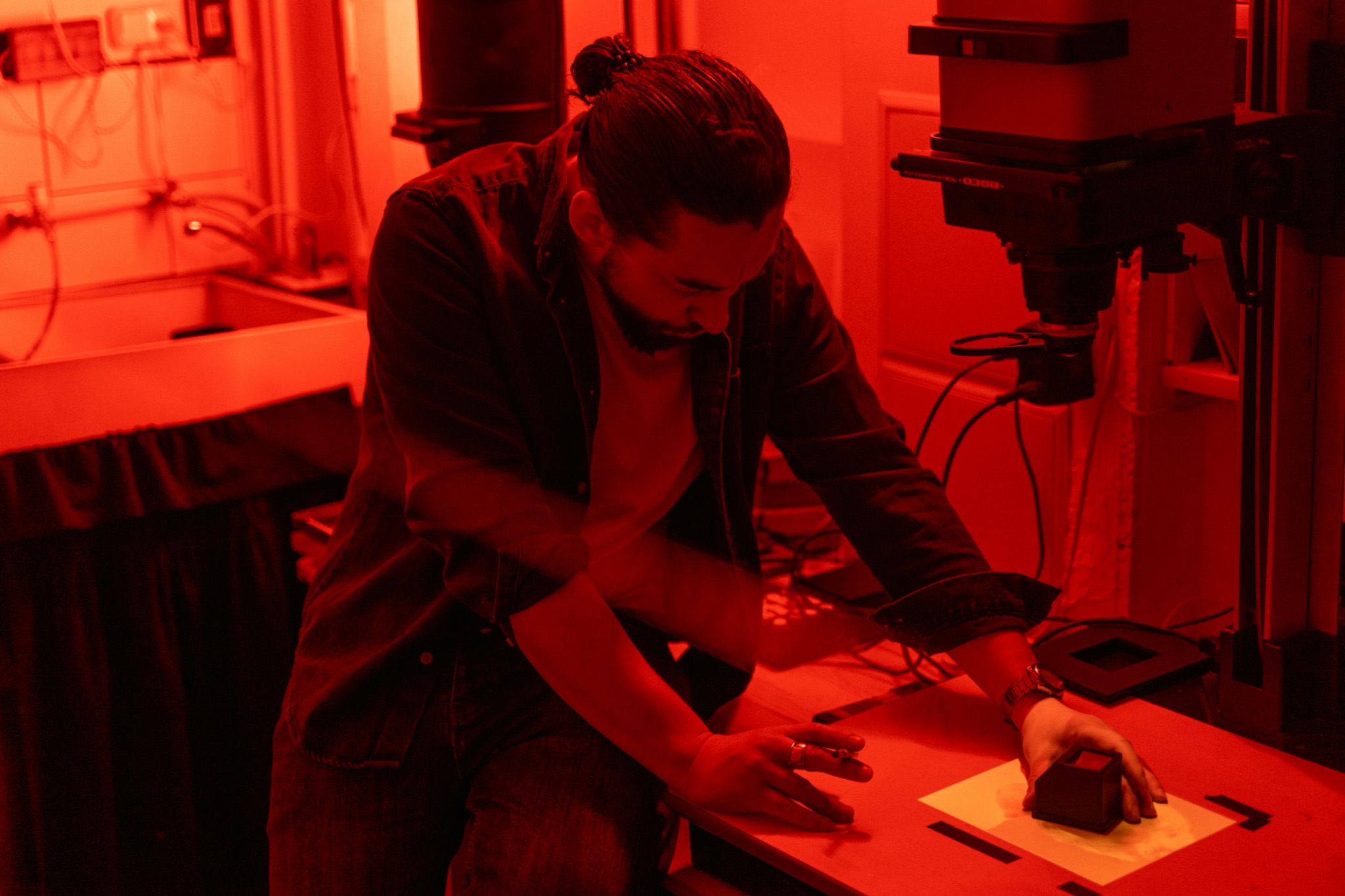Man in darkroom preparing to print black and white film under red light