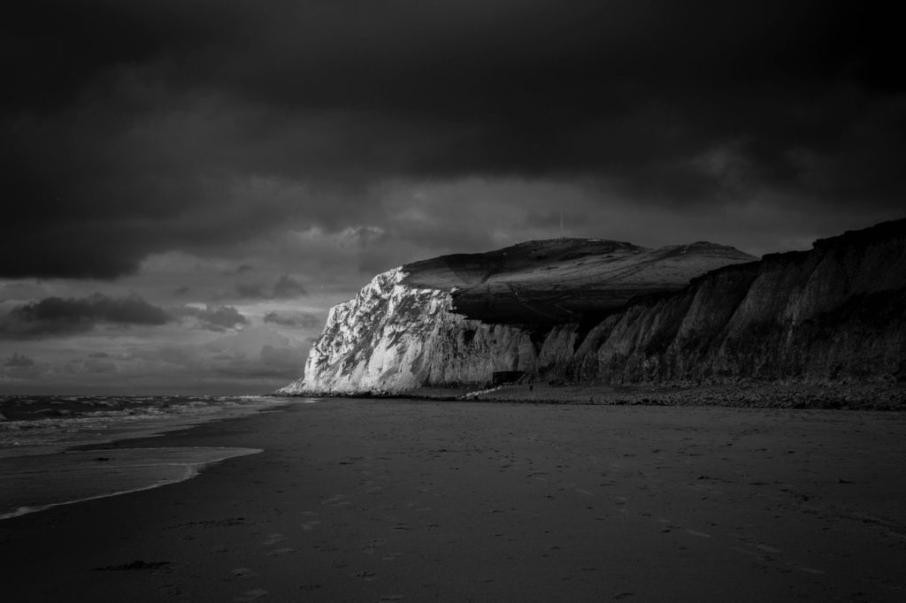 mountain near beach shore under dark cloudy sky