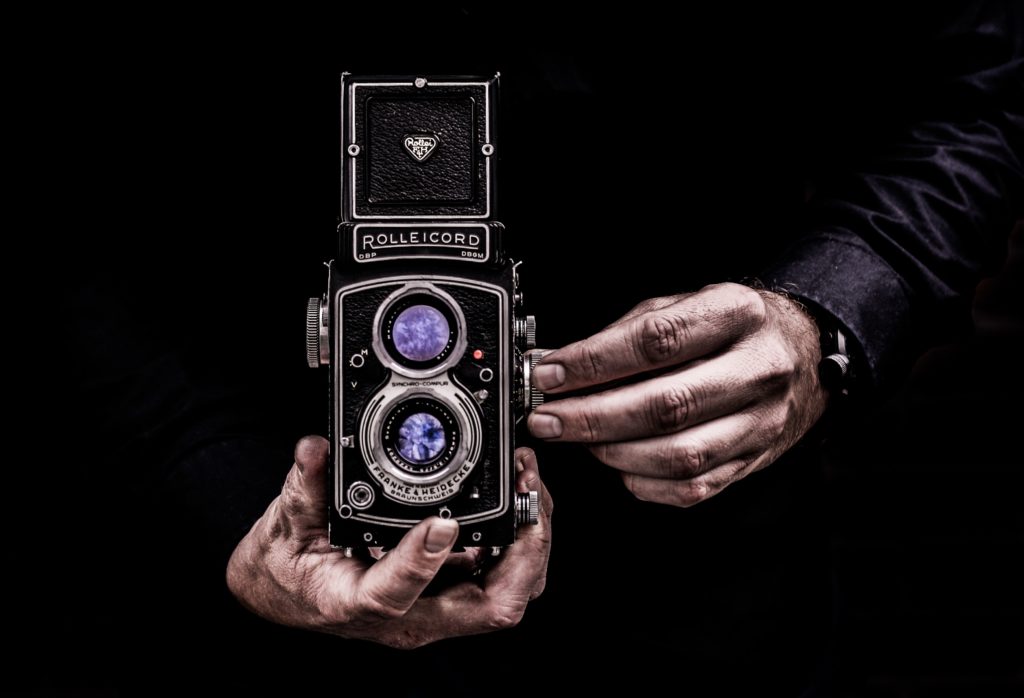 person holding black twin lens reflex camera