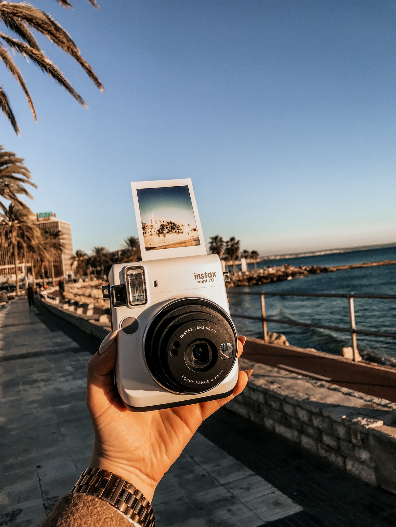 person holding instax mini near sea