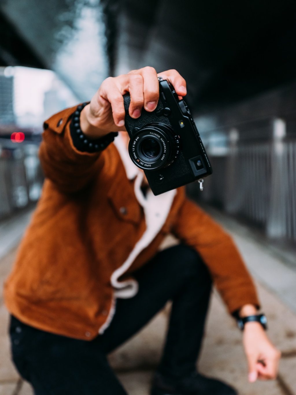 person in brown jacket holding black camera