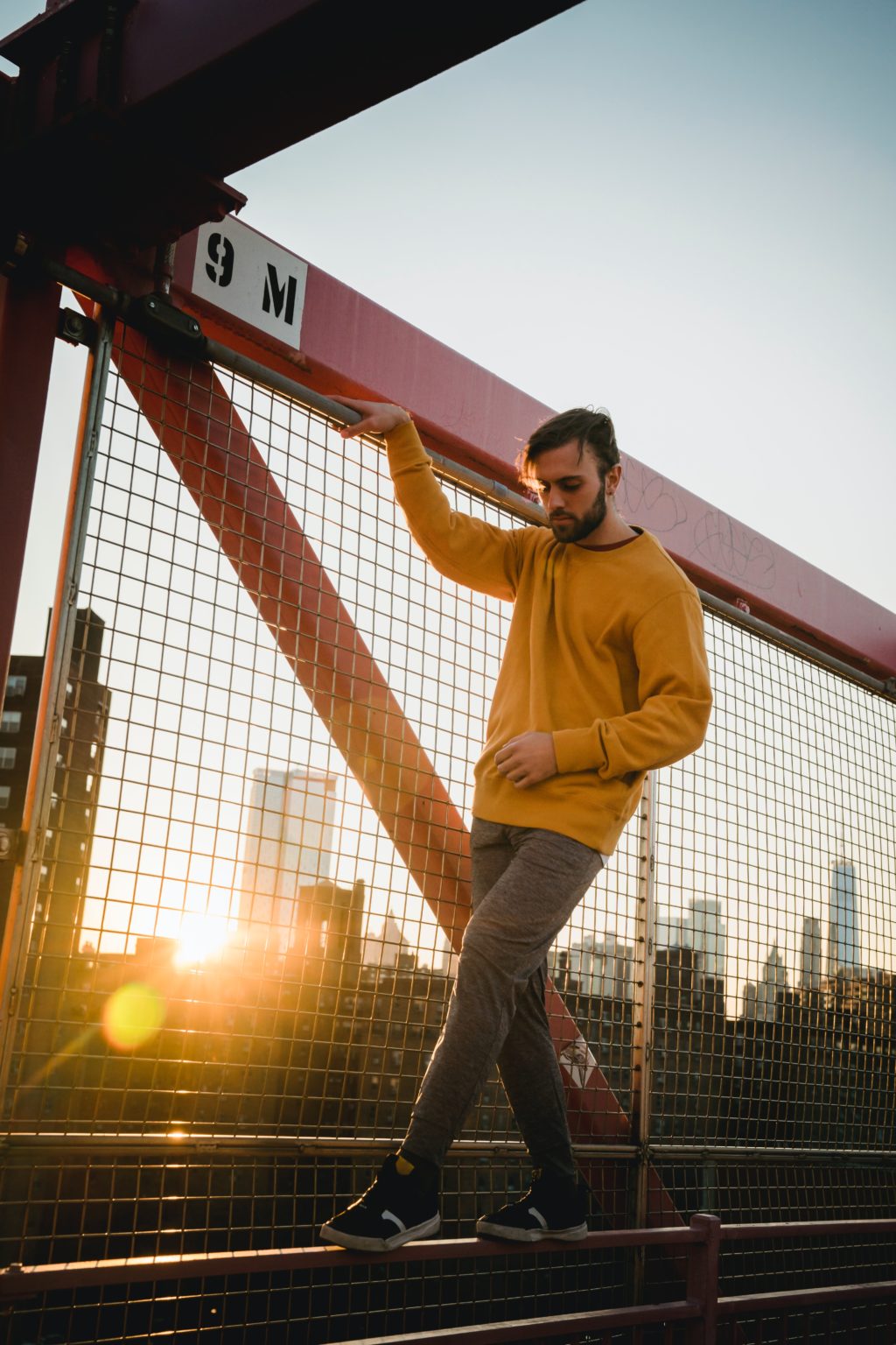 Portrait of man standing by fennce backlit by sun with lens flare.