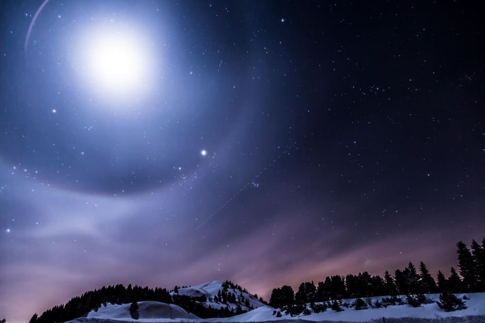 the moon, night sky, and stars with snowy landscape