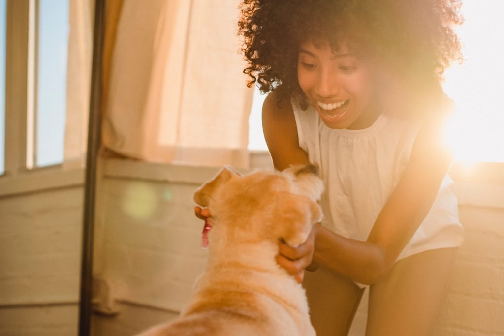 Backlit shot of woman with dog enhanced by lens flare. 