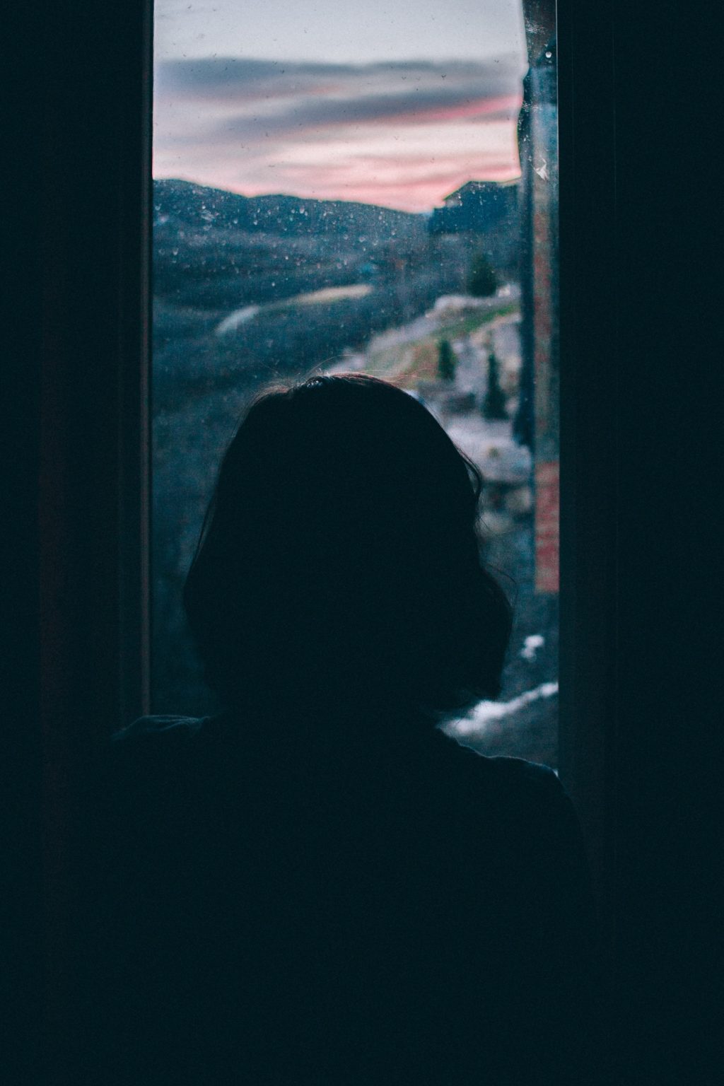 woman looking through a rainy window
