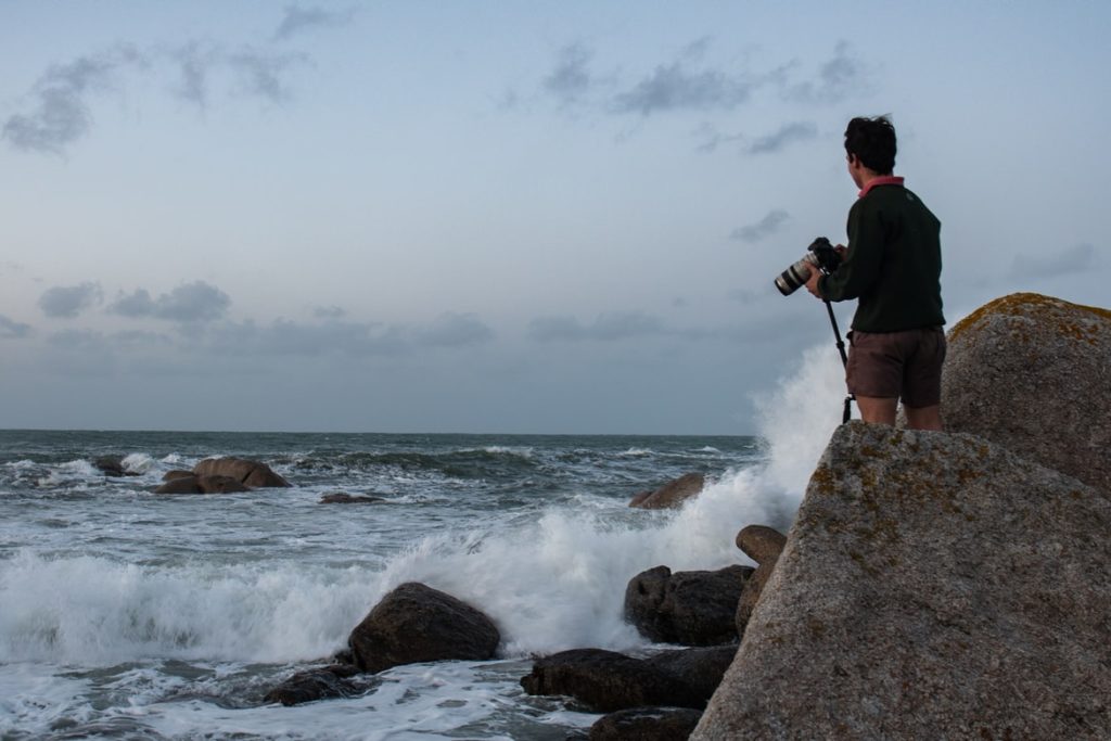 a man standing on a rock looking at the sea