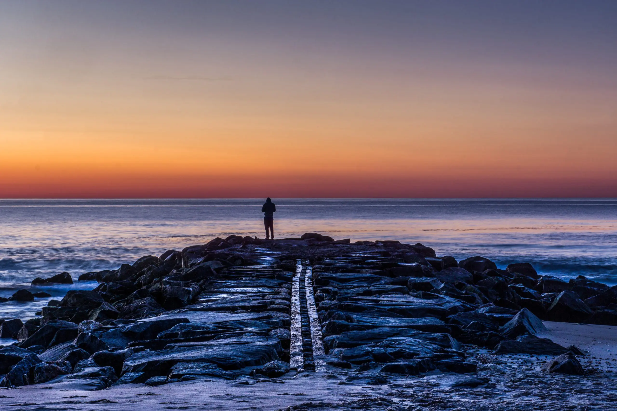 person standing on rocks silhouette