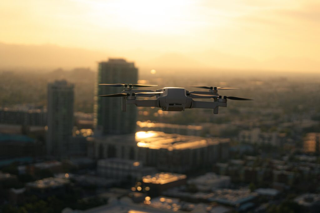 A DJI Mini drone flying in an urban environment. 
