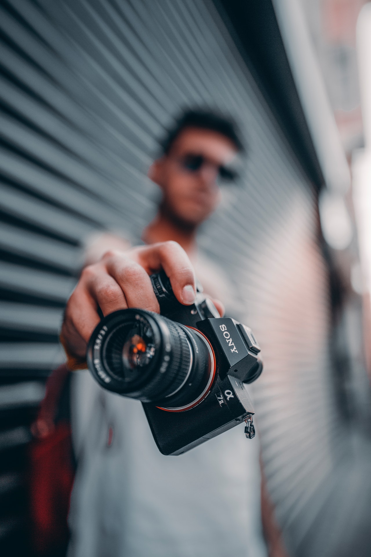 standing man holding black sony dslr camera