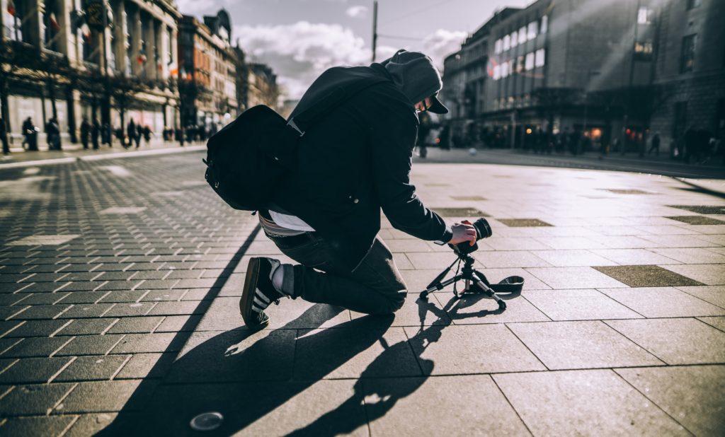 Man taking low angle photograph in a city street