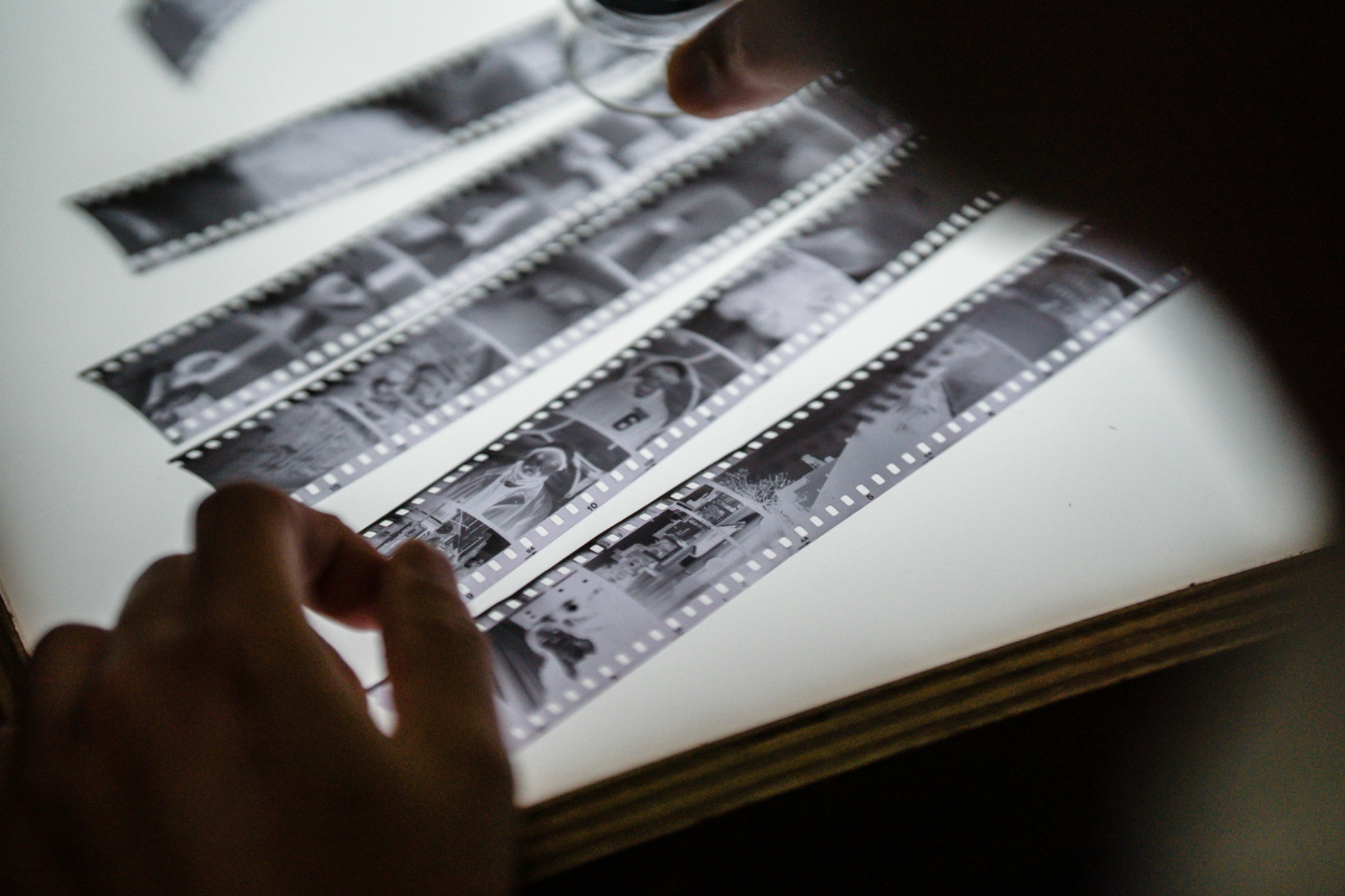 Strips of black and white film on a lightbox with loupe