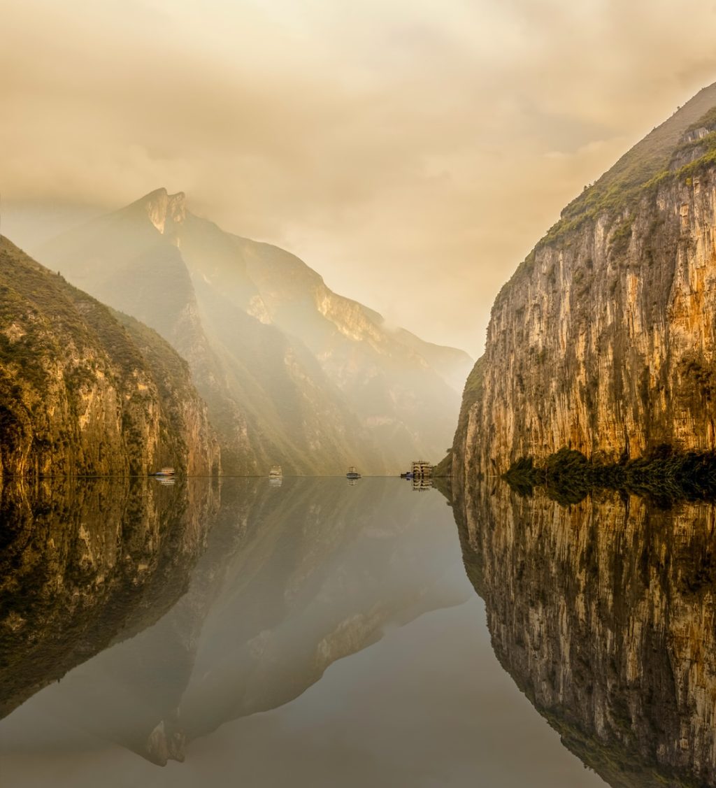 water between rocky mountain under white cloudy sky during daytime photo