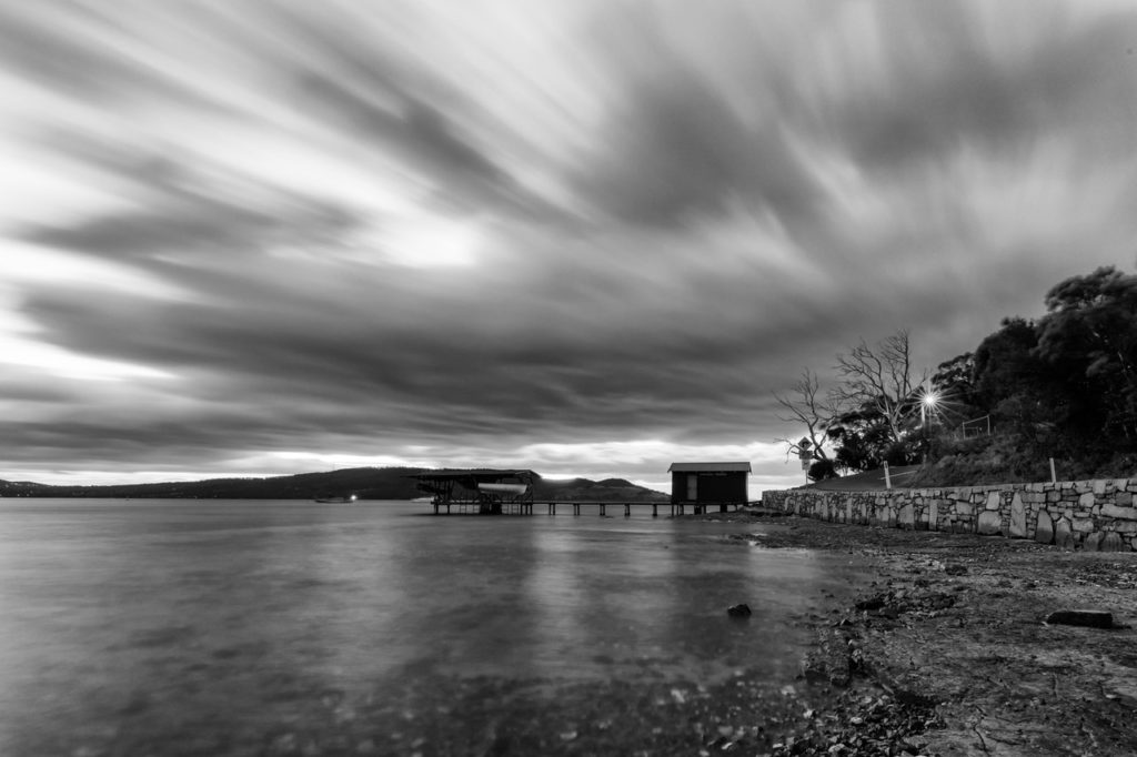 time lapse photo of a house near body of water in grayscale