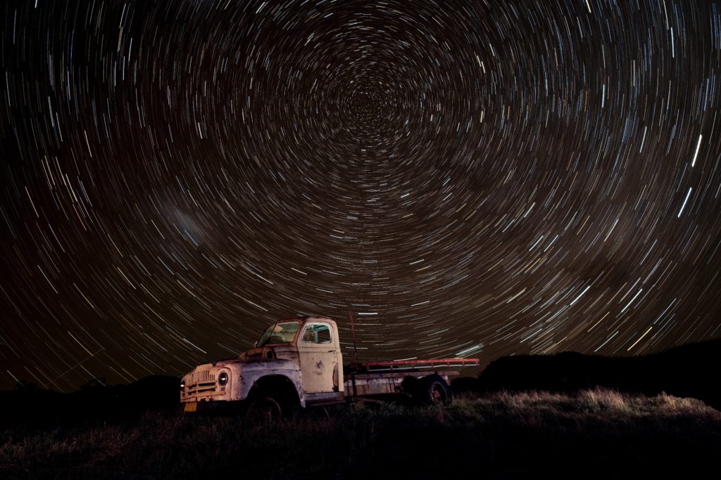 Star trails over a abandoned truck at night