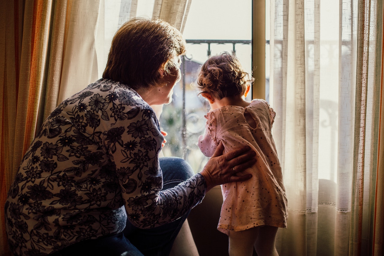 woman holding baby near window