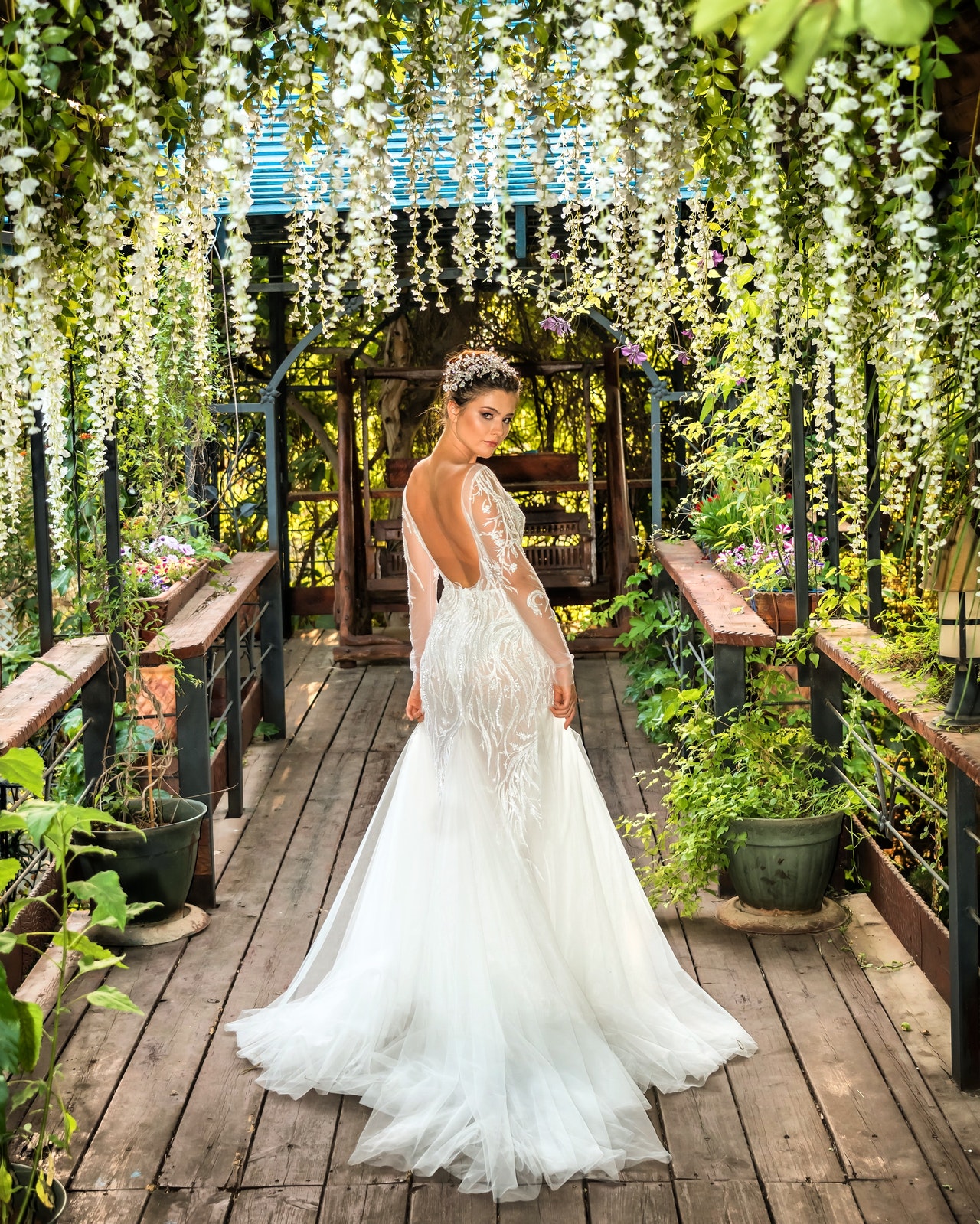 woman in white wedding gown standing on brown wooden pathway