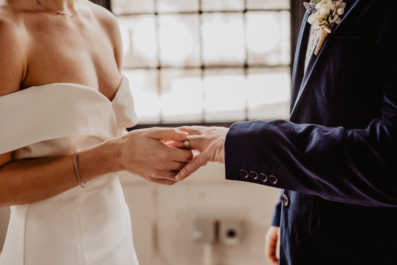 woman putting wedding ring on groom s finger