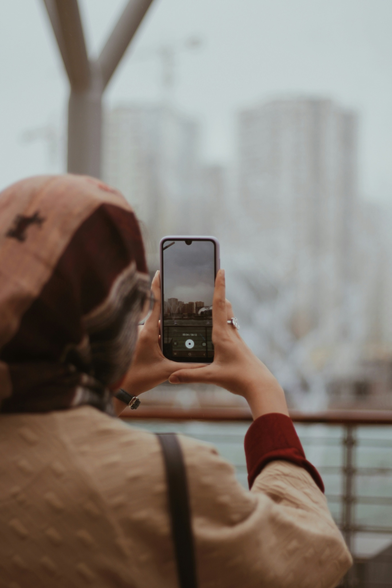 Woman taking smartphone photo of misty skyline